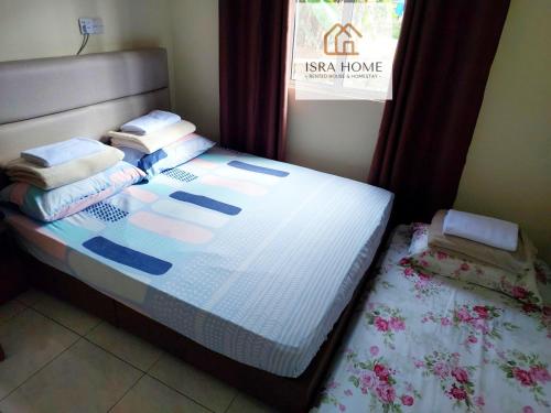 um quarto com uma cama com almofadas e uma janela em ISRA HOME em Ranau