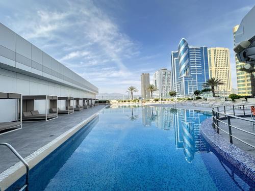 a swimming pool in the middle of a city with tall buildings at Ibis Fujairah in Fujairah