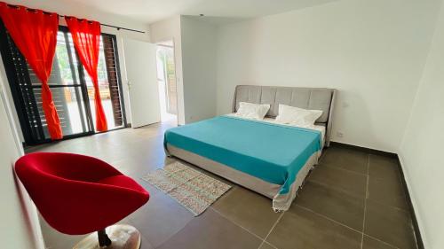 een slaapkamer met een bed en een rode stoel bij La Médina Majunga in Mahajanga