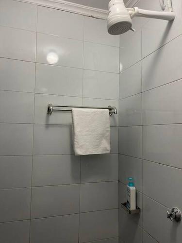 - biały prysznic wyłożony kafelkami z białym ręcznikiem i lampką w obiekcie The Hillmaac Nest 1 Eldoret w mieście Eldoret