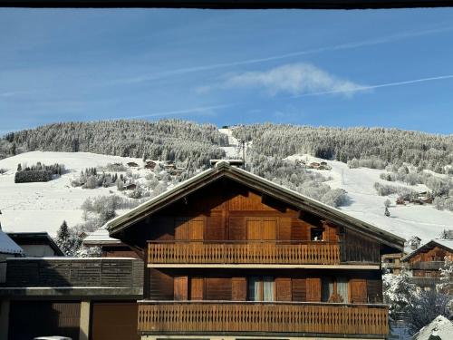 a log cabin with a snow covered mountain in the background at Au Petit Flocon - Appartement 3 pièces, central et proche pistes - parking privé et wifi in Megève