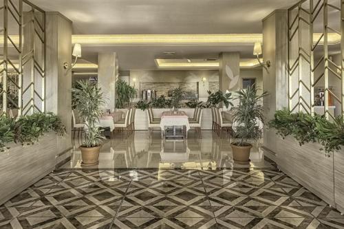 a lobby with a table and chairs and plants at Kustur Club Holiday Village - All Inclusive in Kusadası