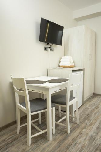 a white dining room table with two chairs and a tv at Arima city in Shumen