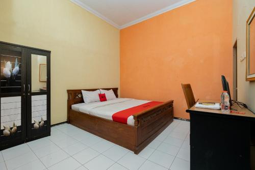 a bedroom with a bed and a desk with a computer at RedDoorz Syariah at Jalan Sunan Giri Tuban in Tuban