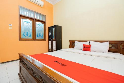 a bedroom with a large bed with a red pillow at RedDoorz Syariah at Jalan Sunan Giri Tuban in Tuban