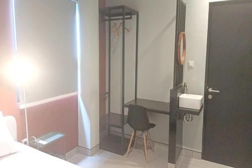 y baño con ducha, silla y lavamanos. en OYO 93514 Rubina Syariah Hotel en Purbolinggo