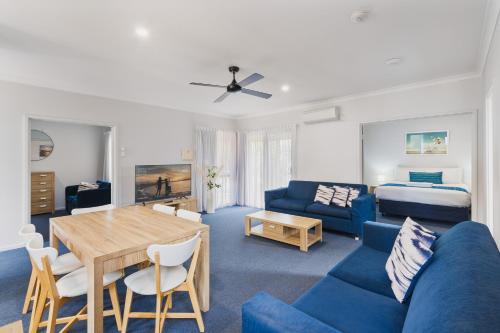 a living room with a blue couch and a table at Amalfi Resort in Busselton