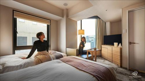 a woman standing on two beds in a hotel room at Daiwa Roynet Hotel Shimbashi in Tokyo