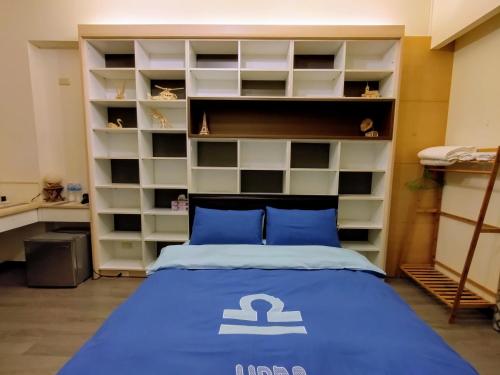 a bedroom with a bed with blue pillows and shelves at 1986 Travel Hall in Tainan