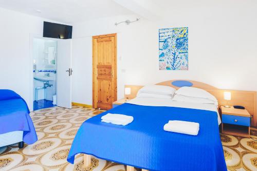 a blue bed in a room with a bathroom at Hotel Ferdinando Beach & Thermal Spa in Ischia