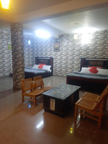 Habitación con 2 camas, 2 sillas y mesas. en Sita Chalet Manali en Manāli