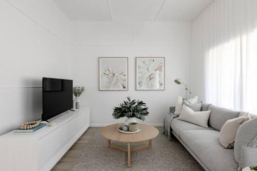 sala de estar blanca con sofá y TV en Casa Wilde in the Hunter en Cessnock