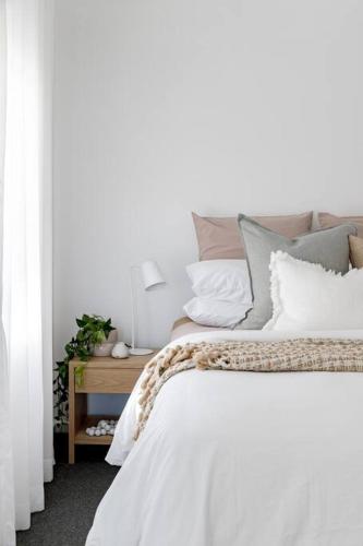 a bedroom with a bed with white sheets and pillows at Casa Wilde in the Hunter in Cessnock