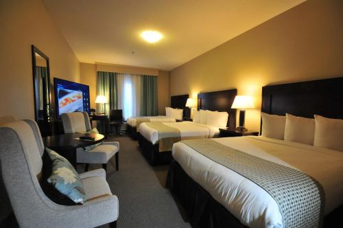 a hotel room with two beds and a flat screen tv at Ramada by Wyndham Emerald Park/Regina East in Regina