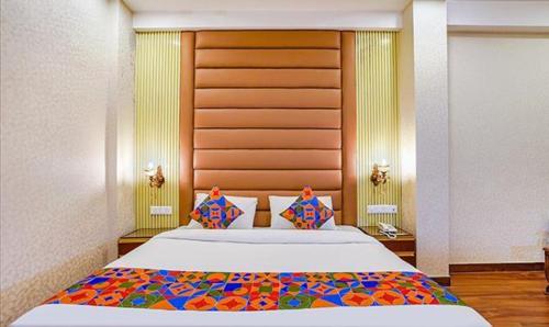 a bedroom with a large bed with a wooden headboard at FabHotel Prime Noida Sector 63 in Noida