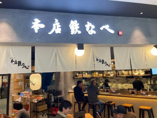 OrioゲストハウスＥn プレザント203的一群人坐在餐厅柜台上
