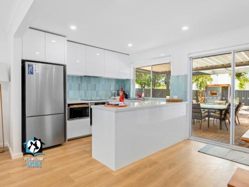 a white kitchen with a refrigerator and a table at Hampton's Style Holiday Retreat - close to the beach! in Encounter Bay