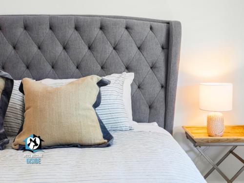 a bed with a gray headboard and a table at Hampton's Style Holiday Retreat - close to the beach! in Encounter Bay