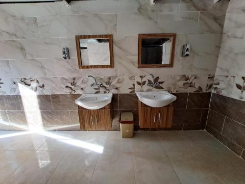 a bathroom with two sinks and two mirrors at Wadi Rum Bedouin Heart Camp in Wadi Rum