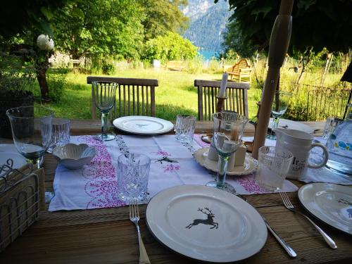a wooden table with plates and wine glasses on it at Countryhouse Lake Attersee - Traumhaft schöne Lage - Bezauberndes Hideaway in Unterach am Attersee