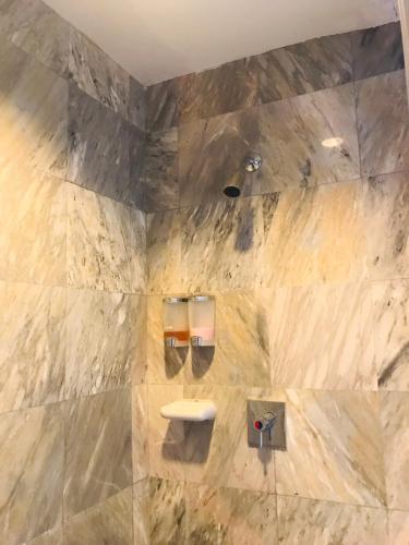 a bathroom with a stone wall with a toilet at Saensukkho Hotel & Resort in Chiang Rai