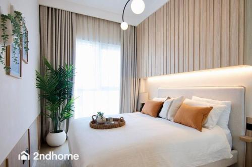 een slaapkamer met een groot wit bed met een plant bij Coziest 2 Bedroom In Collective, Dubai Hills by 2ndhome in Dubai