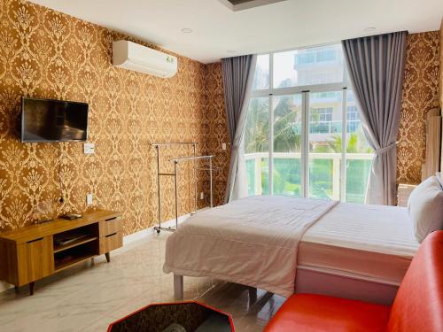 um quarto com uma cama, uma televisão e uma janela em Căn hộ Ocean Vista 1br Garden View - SeaHome em Phan Thiet