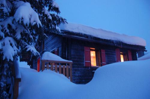 a house covered in snow with lights on it at BnB Le Mazot Fionnay in Fionnay