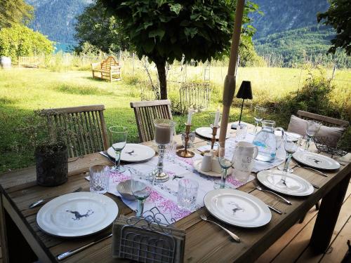 a wooden table with plates and glasses on it at Countryhouse Lake Attersee - Traumhaft schöne Lage - Bezauberndes Hideaway in Unterach am Attersee