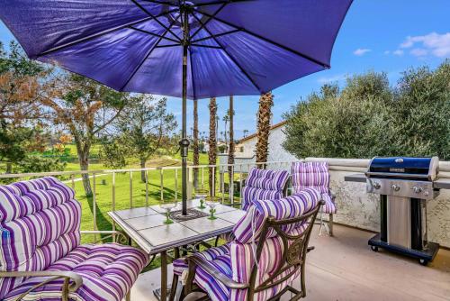 a patio with purple chairs and a table with an umbrella at Idyll in the Desert - Immaculate Palm Desert Getaway in Palm Desert