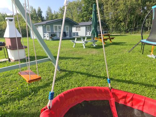 a playground with a swing in a yard at Domki Przy Marinie Wapnica 6 km od Międzyzdrojów in Wapnica