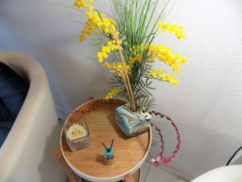 une table avec un vase avec des fleurs jaunes sur lui dans l'établissement Saint Palais sur Mer - COEUR du PLATIN - VILLA en RESIDENCE 5 min PLAGE, à La Palud