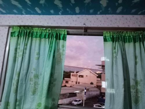 uma janela com cortinas verdes num quarto em QUICKSHAPE FITNESS GYM/QUICKSHIELD HOMESTAY em Naga