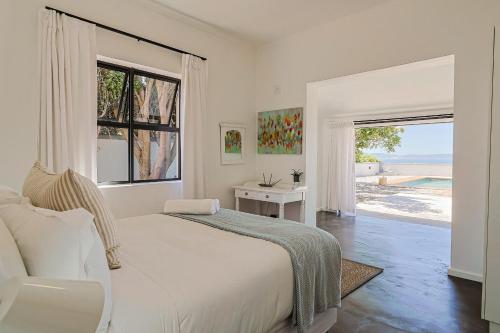 a white bedroom with a large bed and a window at 38 on Westcliff in Hermanus
