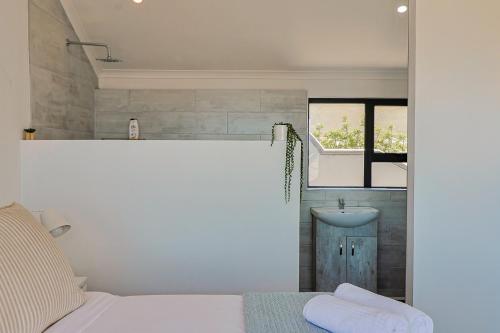 a bedroom with a white bed and a sink at 38 on Westcliff in Hermanus
