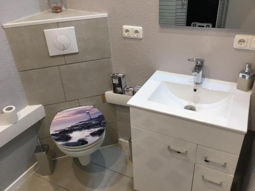 a bathroom with a sink and a toilet with a picture on the lid at Hafenwohnung in Borgwedel