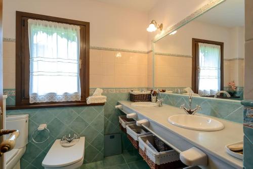 a bathroom with two sinks and a toilet and a mirror at La Casina in Cudillero