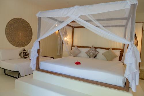 a bedroom with a white bed with a canopy at Alma Boutique Hotel in Jambiani