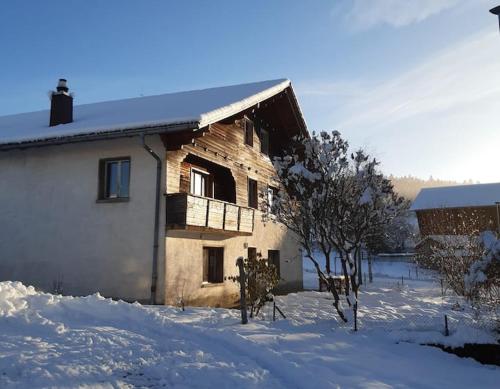 dom ze śniegiem na ziemi obok budynku w obiekcie Böglihuus w mieście Bellelay