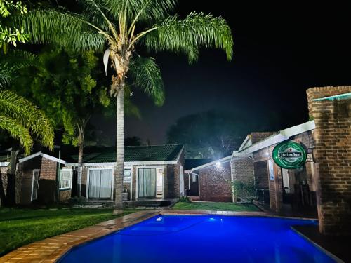 a palm tree in front of a house with a blue pool at SABLE INN B&B in Modimolle