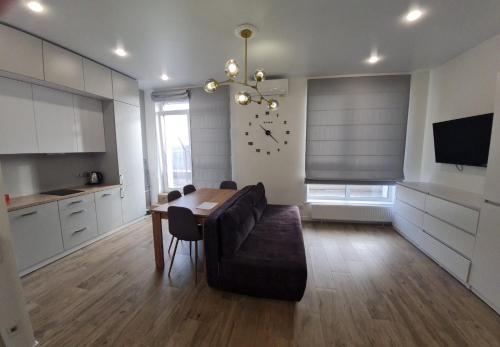 uma sala de estar com uma mesa, um sofá e um relógio em ApartPlus - Затишні апартаменти em Dnipro