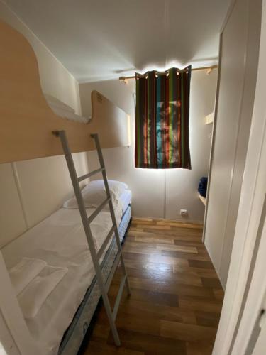 a small room with a bunk bed and a window at Camping Via Romana in Prunelli-di-Fiumorbo