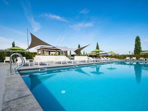 a large swimming pool with white chairs and umbrellas at Holiday Home in Limburg with Outdoor Fireplace in Bemelen