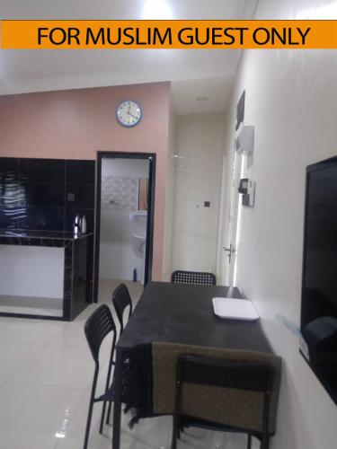 uma sala de jantar com mesa e cadeiras e um relógio em Yasmeen Studio Roomstay Kijal - Room 1 - FOR TWO PERSON ISLAM GUEST ONLY em Kijal