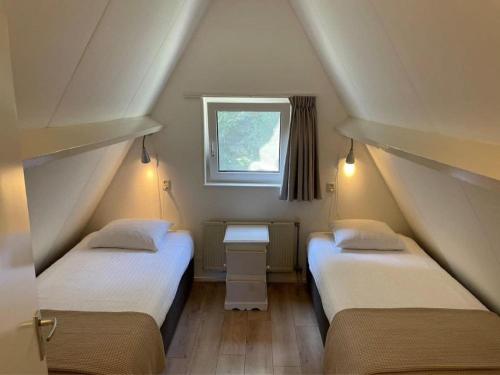 two beds in a small room with a window at Holiday House in Friesland with Garden in Sint Nicolaasga