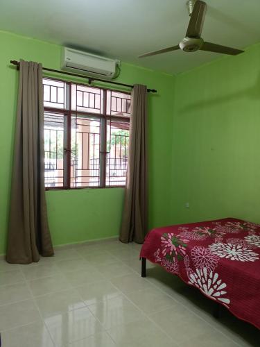 zieloną sypialnię z łóżkiem i oknem w obiekcie Yasmeen Homestay Kemaman w mieście Kampong Kemaman