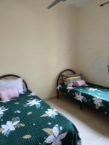 sypialnia z 2 łóżkami z zieloną i białą pościelą w obiekcie Yasmeen Homestay Kemaman w mieście Kampong Kemaman