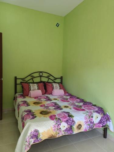 sypialnia z łóżkiem z narzutą kwiatową w obiekcie Yasmeen Homestay Kemaman w mieście Kampong Kemaman