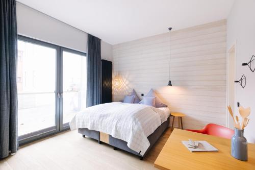 a bedroom with a bed and a desk and a window at Meerloft Norderney in Norderney