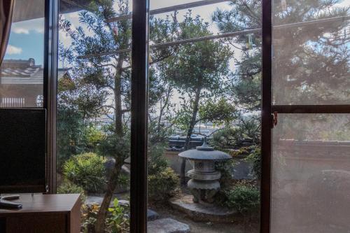a view of a garden through a glass door at 玉島茶室-歴史を感じる和の空間 ペット同伴 バーベキュー可 in Nagao